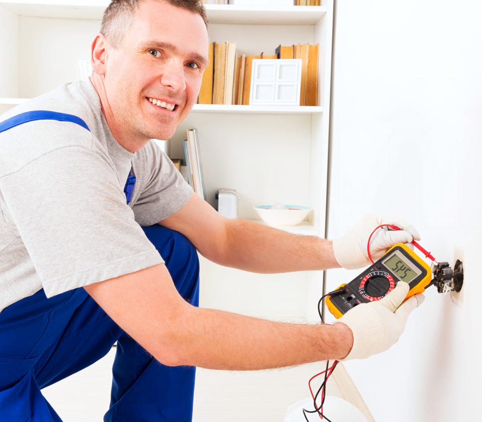 Electrician checking socket voltage with digital multimeter